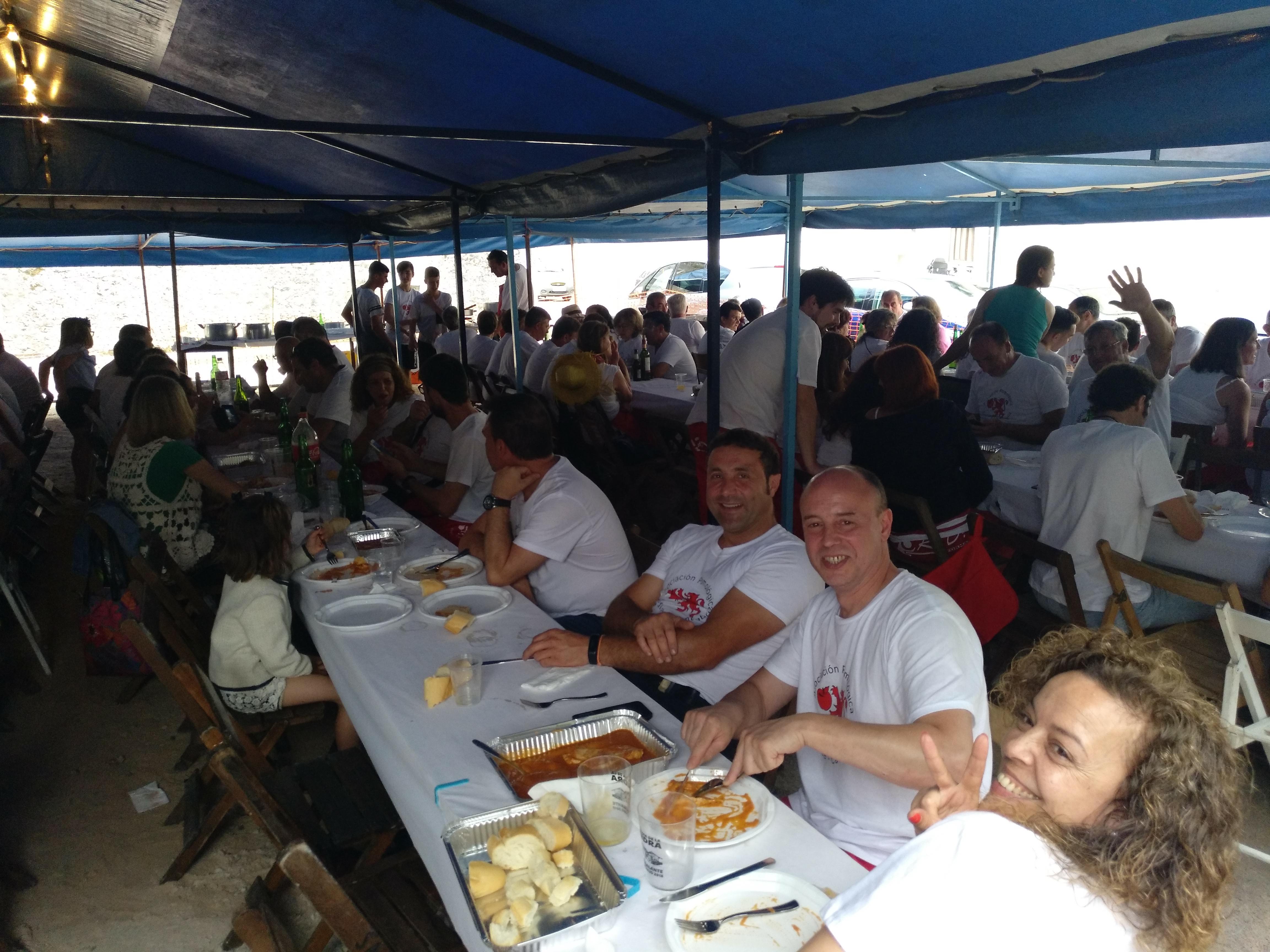 Miembros de la asociación comen juntos en una mesa al aire libre durante la fiesta de la sidra.